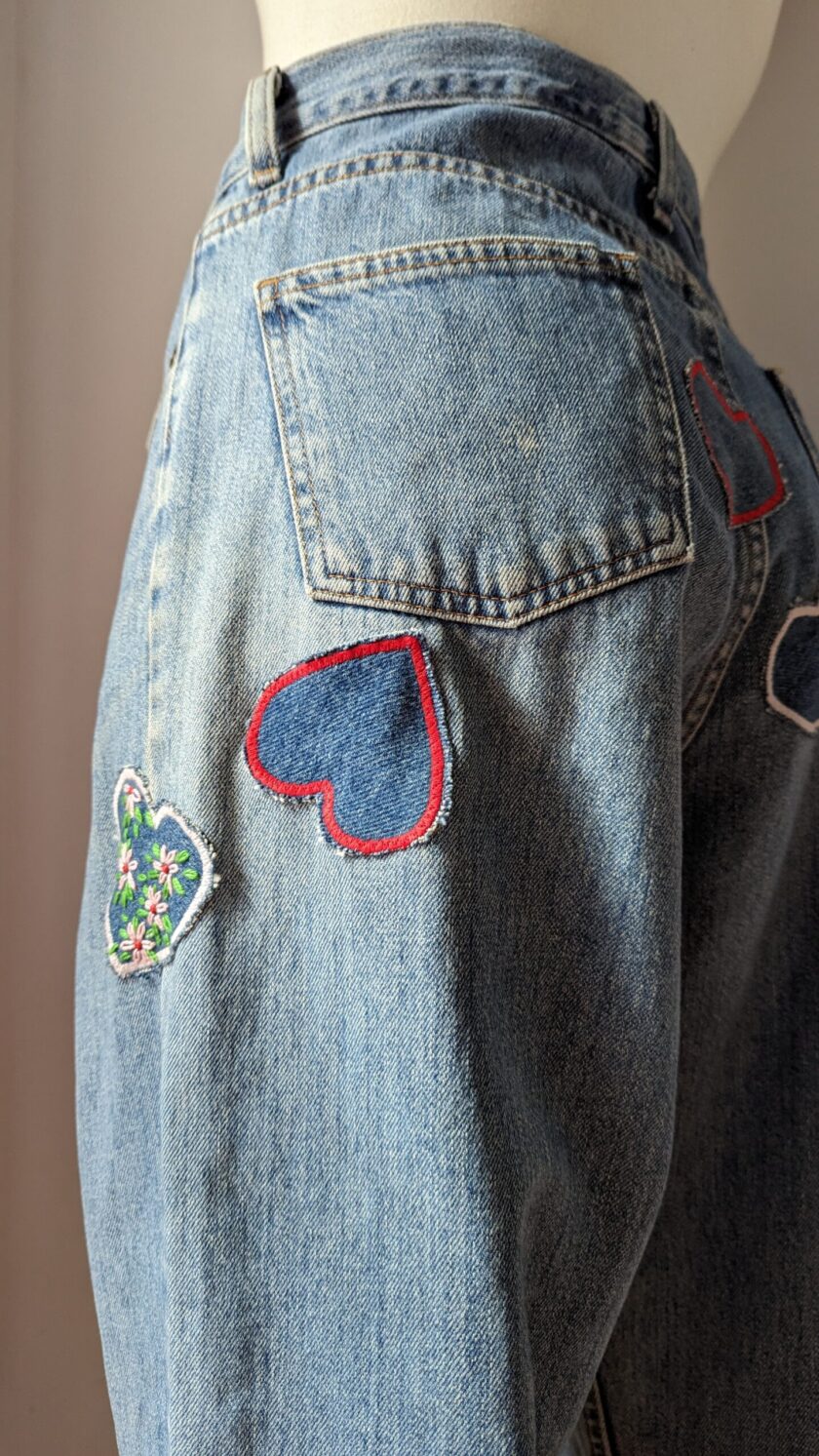 A mannequin wearing a pair of jeans with heart patches.