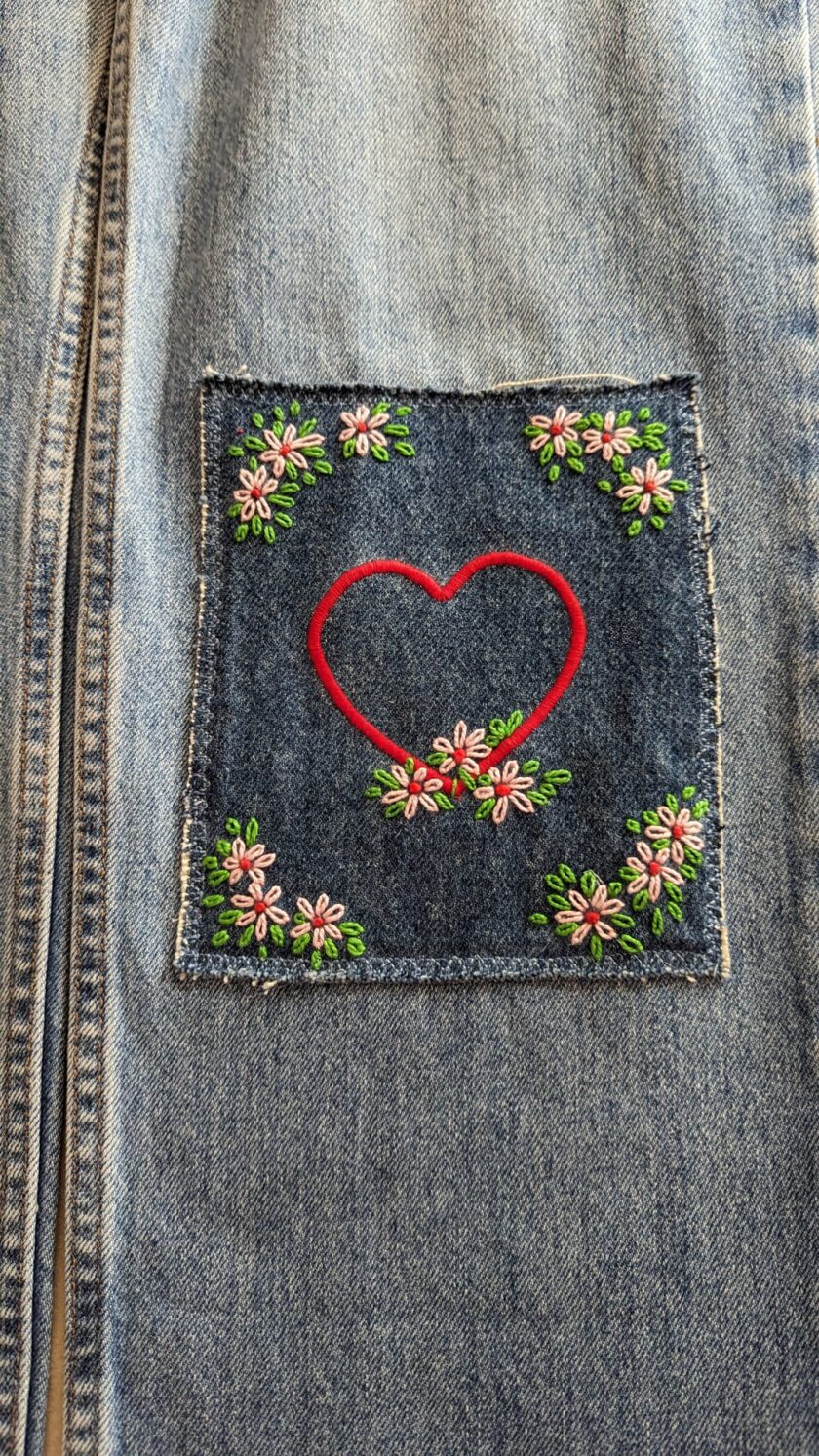 A denim jacket with a heart embroidered on it.