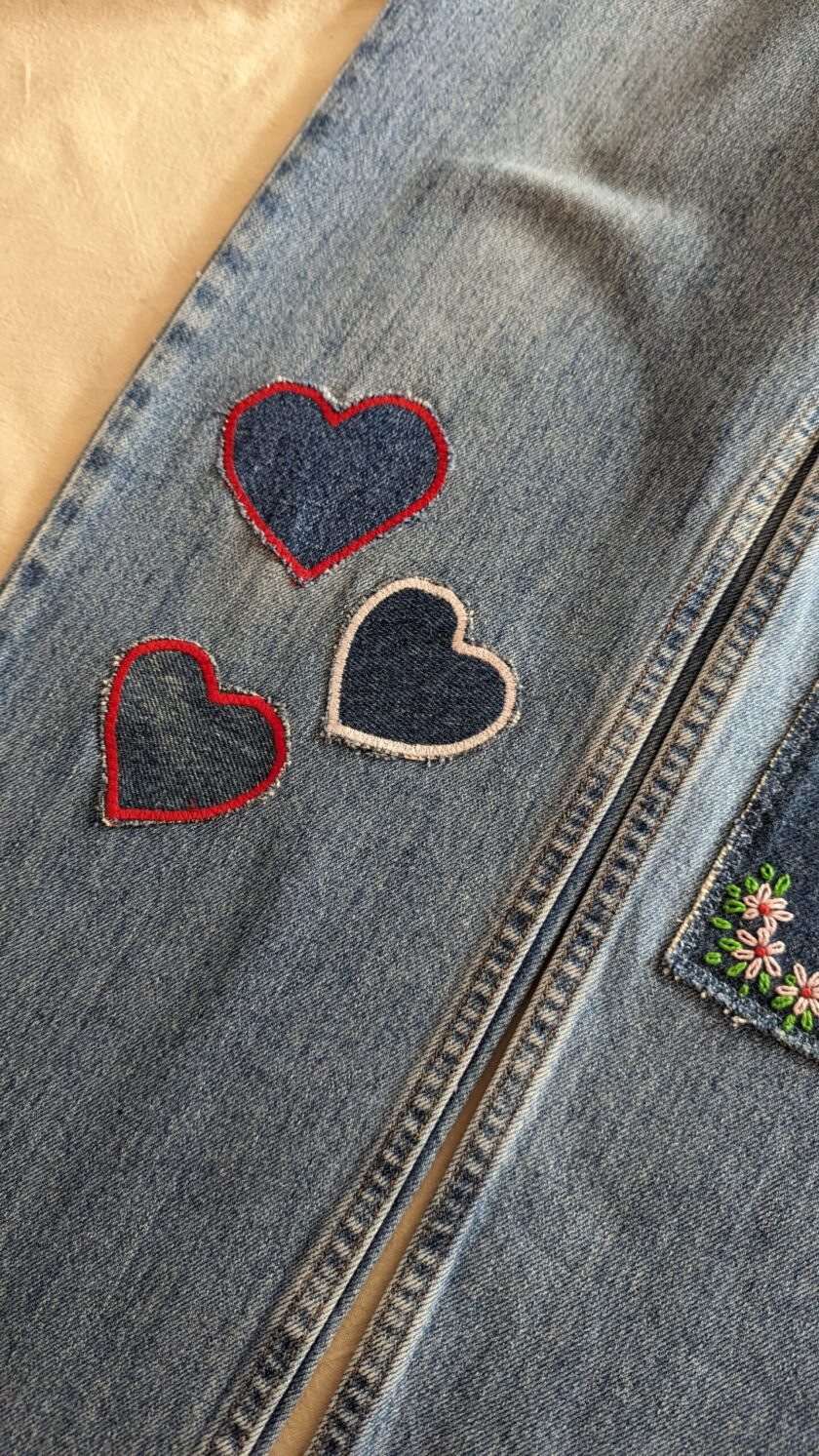 A pair of jeans with hearts embroidered on them.