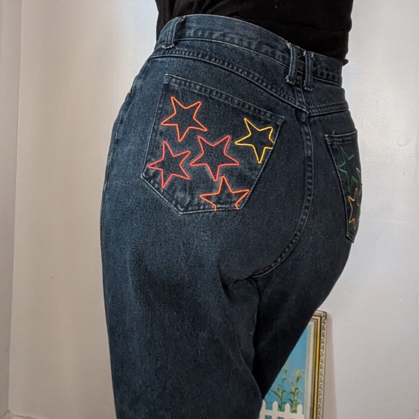 The back of a woman's jeans with stars embroidered on them.