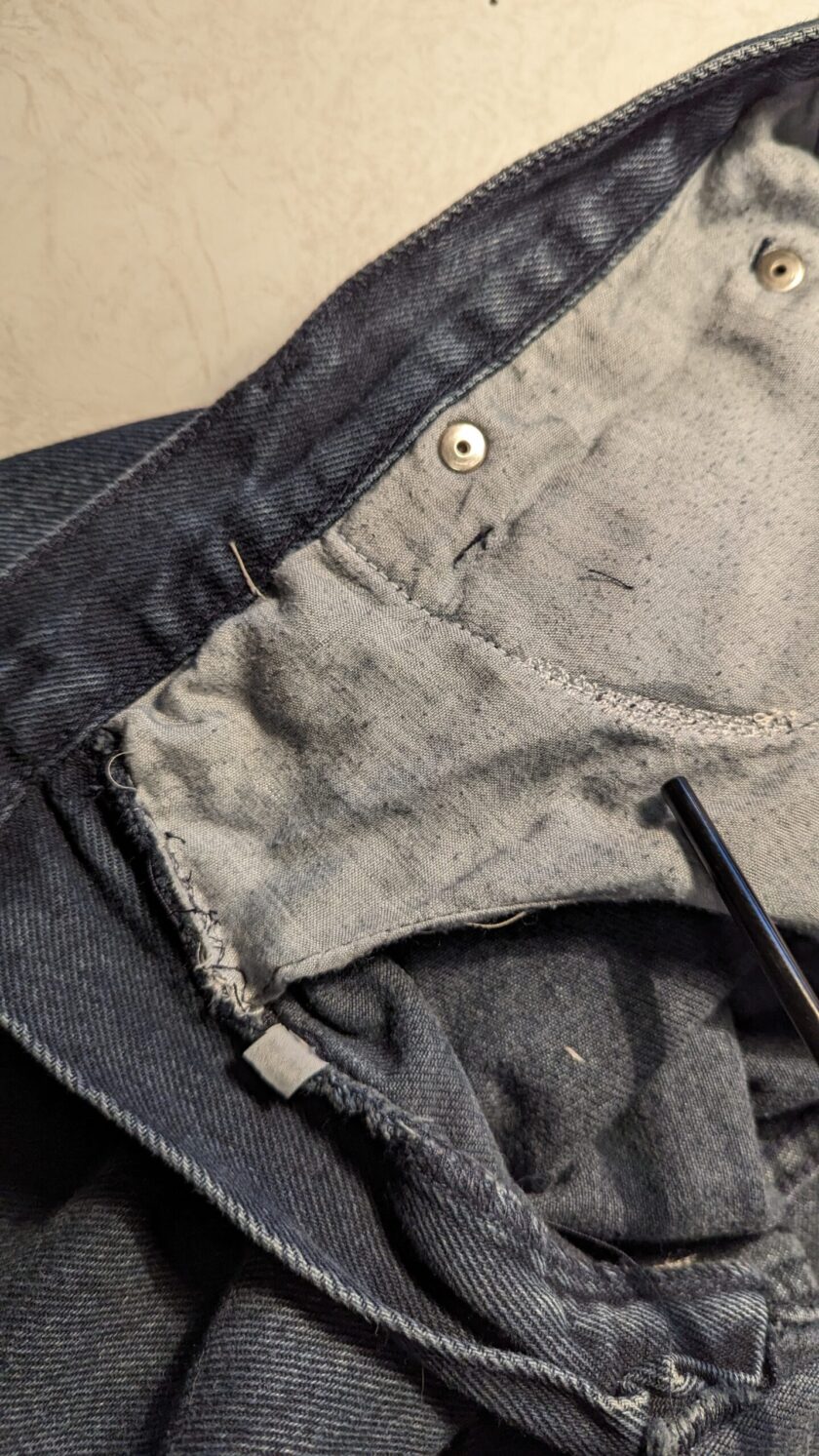 A close up of a pair of jeans with a pair of scissors.