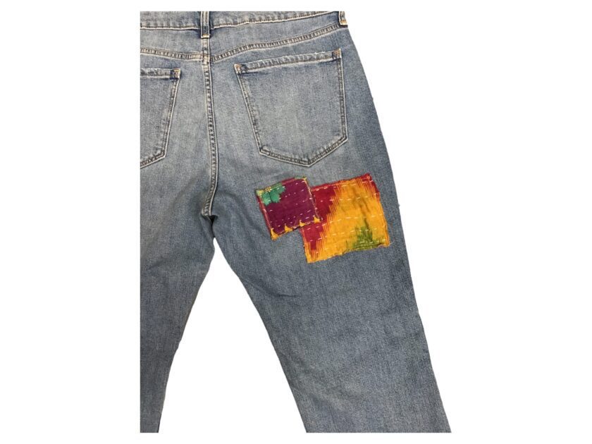 A pair of jeans with a colorful patch on the back.