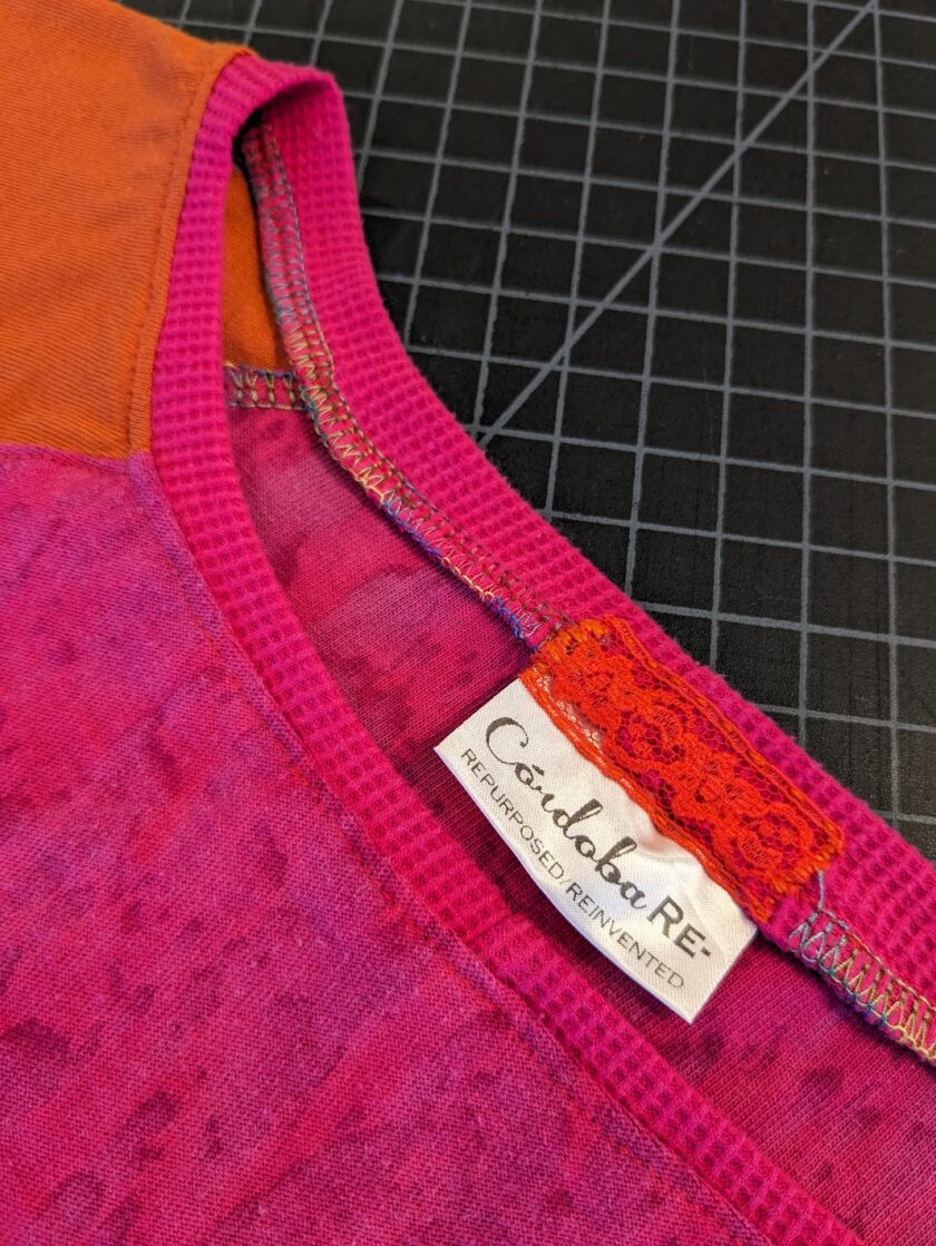 A close up of a pink and orange shirt with a label on it.