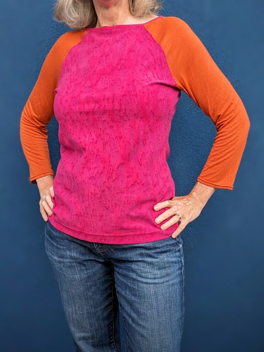 A woman wearing a pink and orange raglan sleeve top.