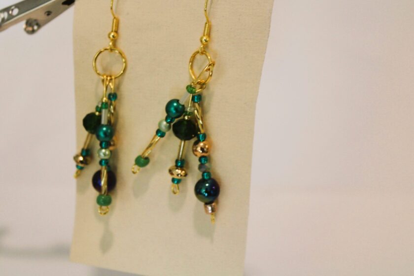 A pair of earrings with green and blue beads.