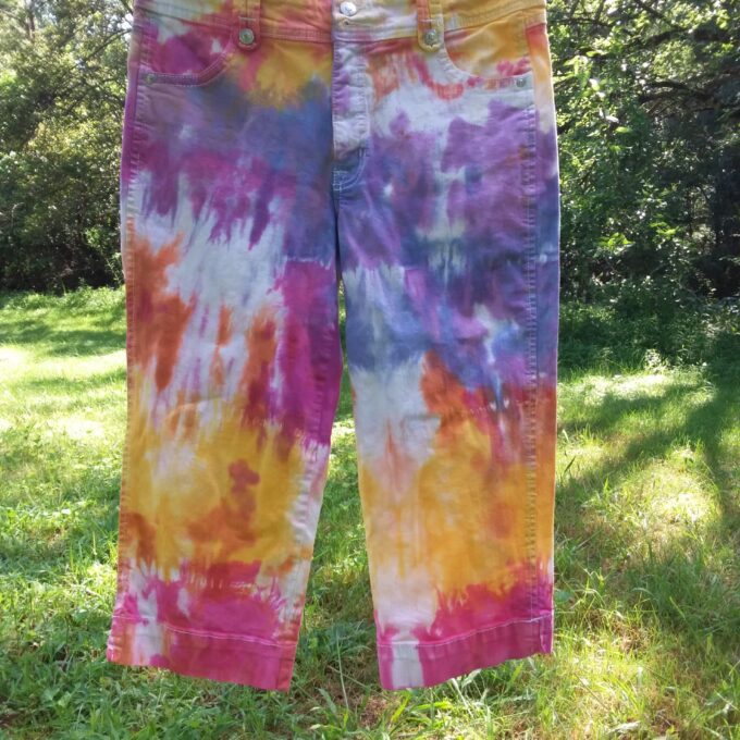 Upcycled tie dyed jeans in shades of pink, yellow, orange, purple and blue.