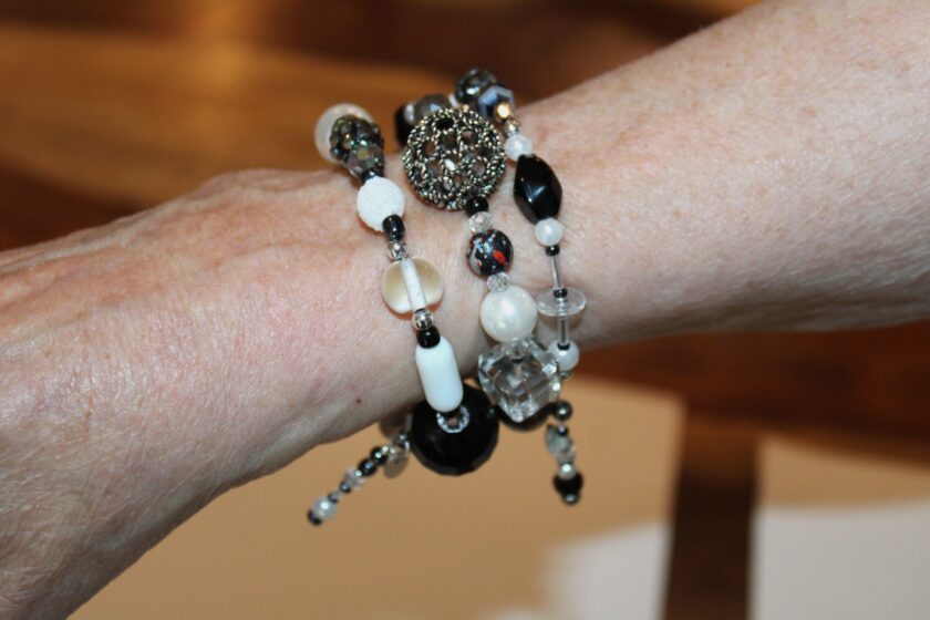 A woman's hand wearing bracelet with black beads and pearls.