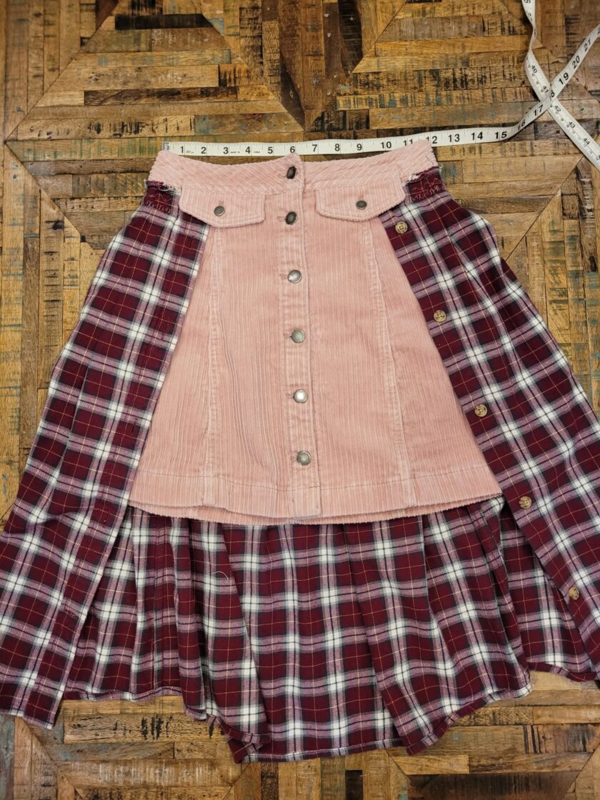 A pink and white plaid skirt on top of a wooden floor.