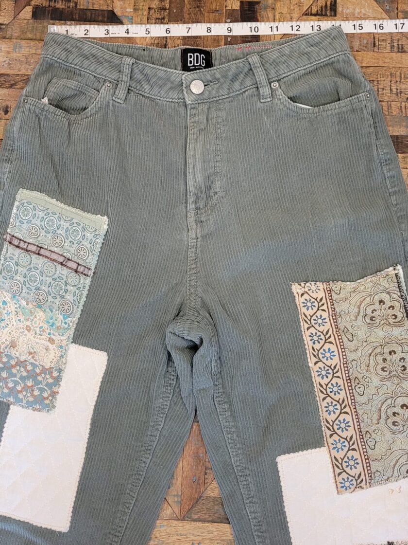 A pair of green corduroy shorts with patches on them.