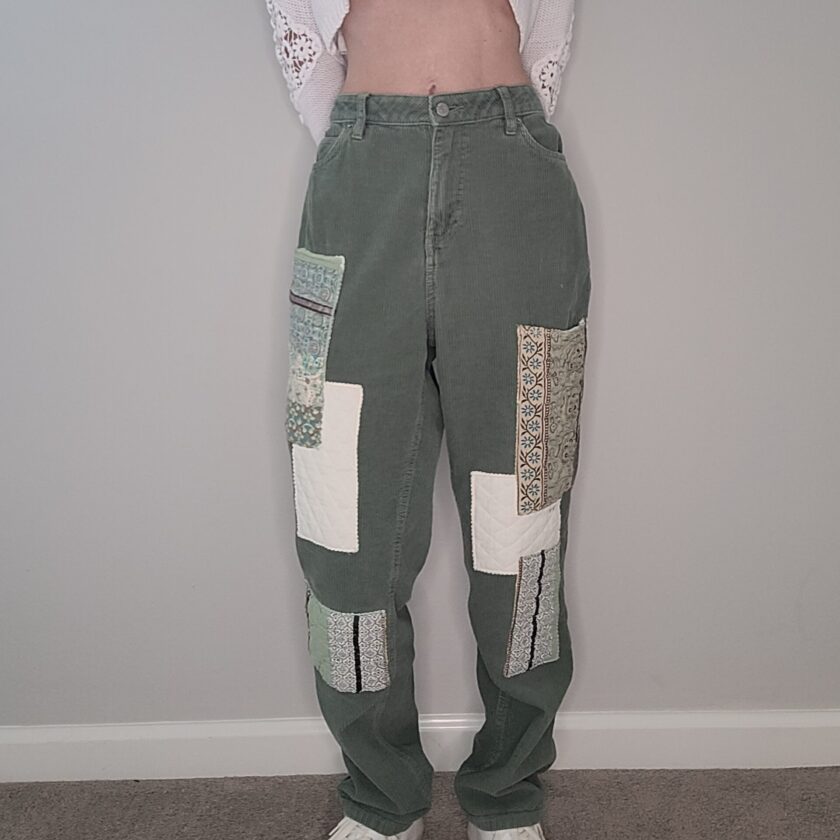 A woman wearing green patchwork pants and a white crop top.