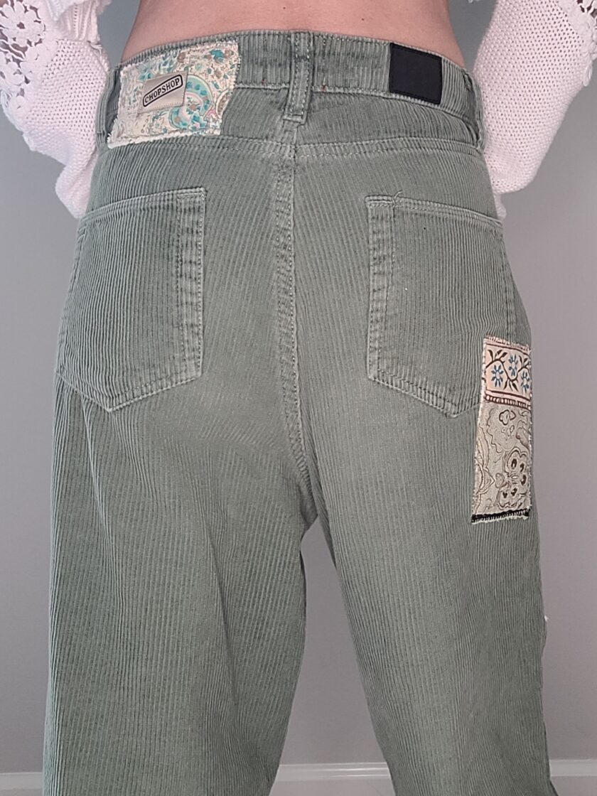The back view of a woman wearing green corduroy pants.