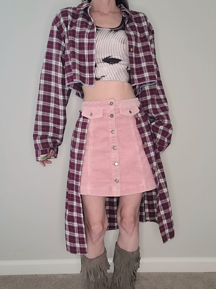 A woman wearing a plaid shirt and pink skirt.