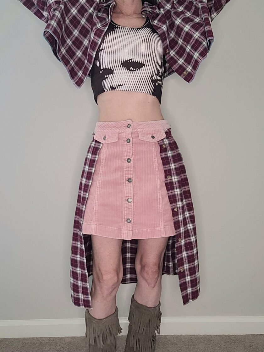 A woman wearing a plaid shirt and pink skirt.