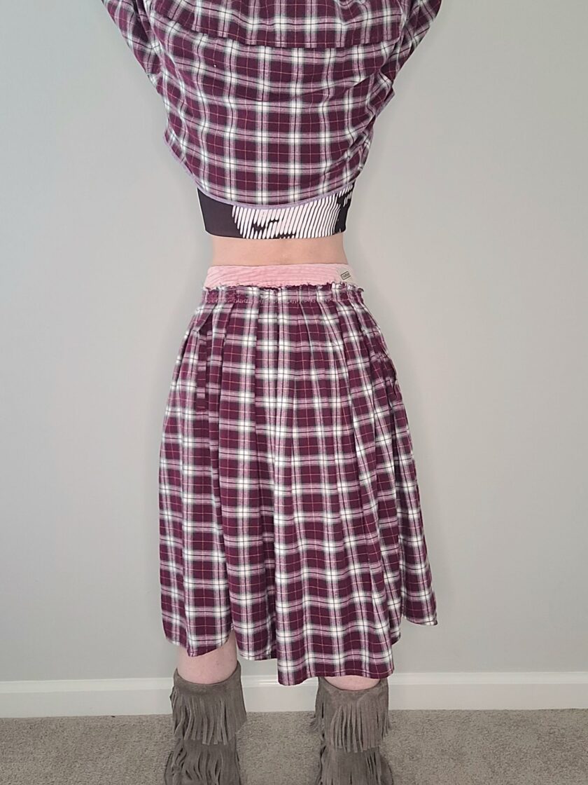 A mannequin wearing a plaid skirt and boots.