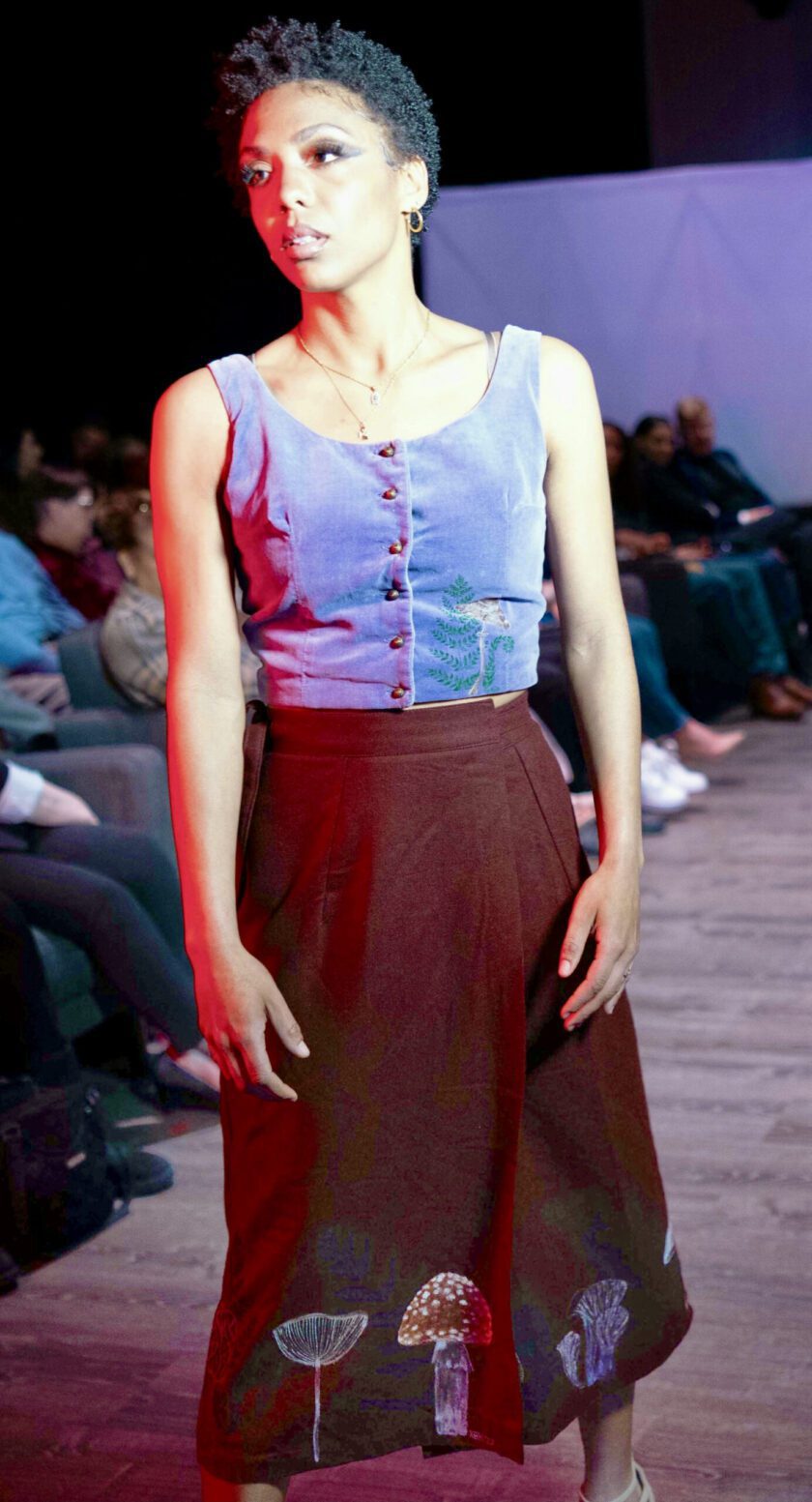 A woman wearing a skirt and top on a runway.