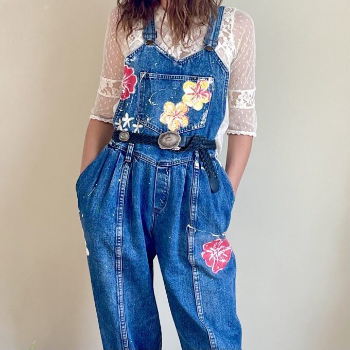 A woman wearing a denim overall with flowers on it.