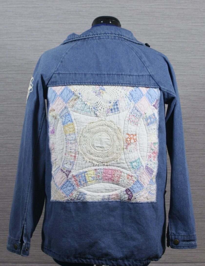 A blue denim jacket with a patchwork quilt on it.