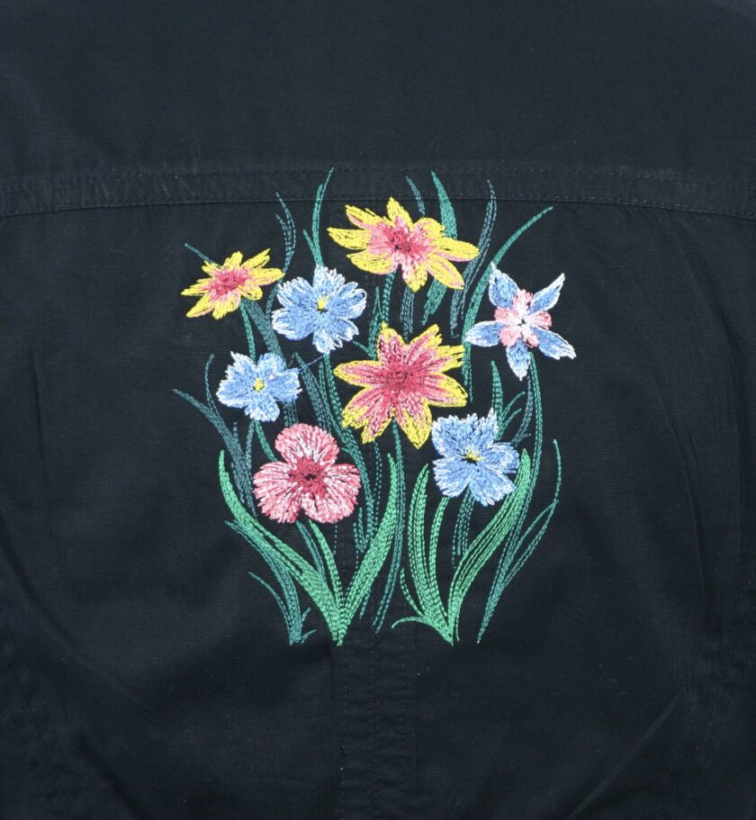 The back of a black jacket with flowers embroidered on it.