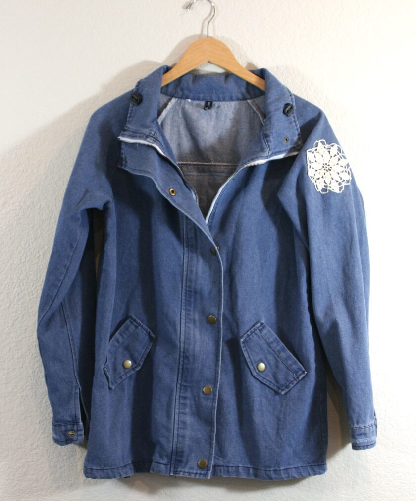 A blue denim jacket hanging on a wall.