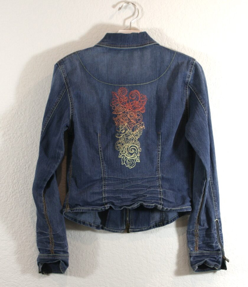 A denim jacket with an embroidered flower on it.