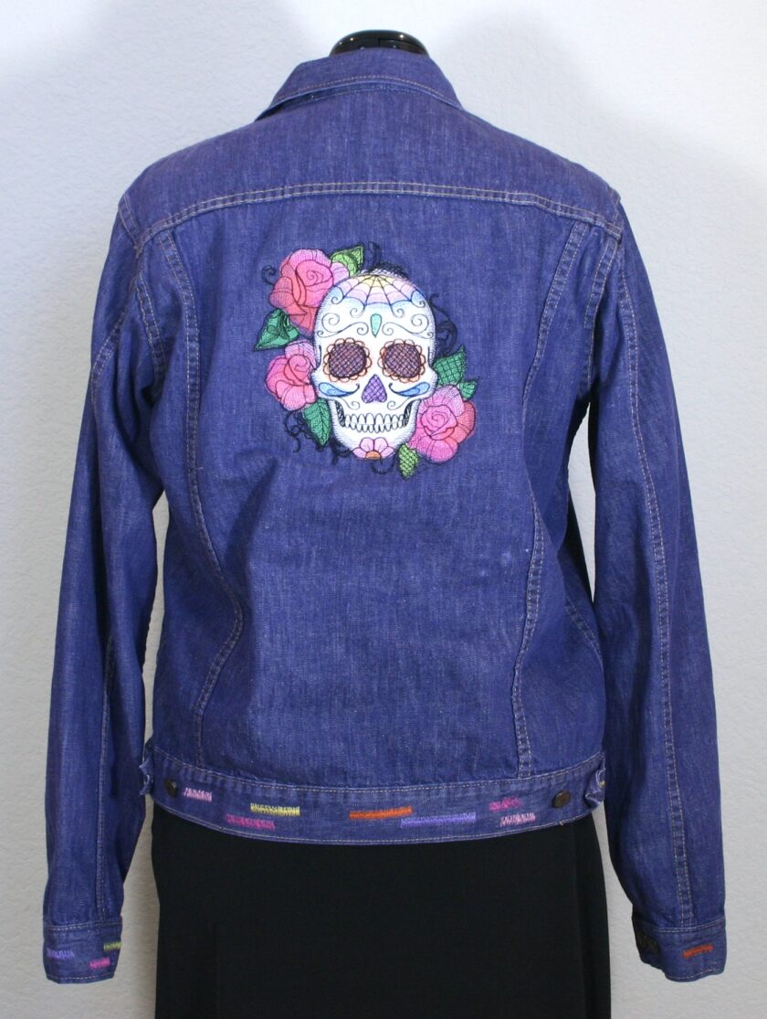 A denim jacket with a skull and roses embroidered on it.