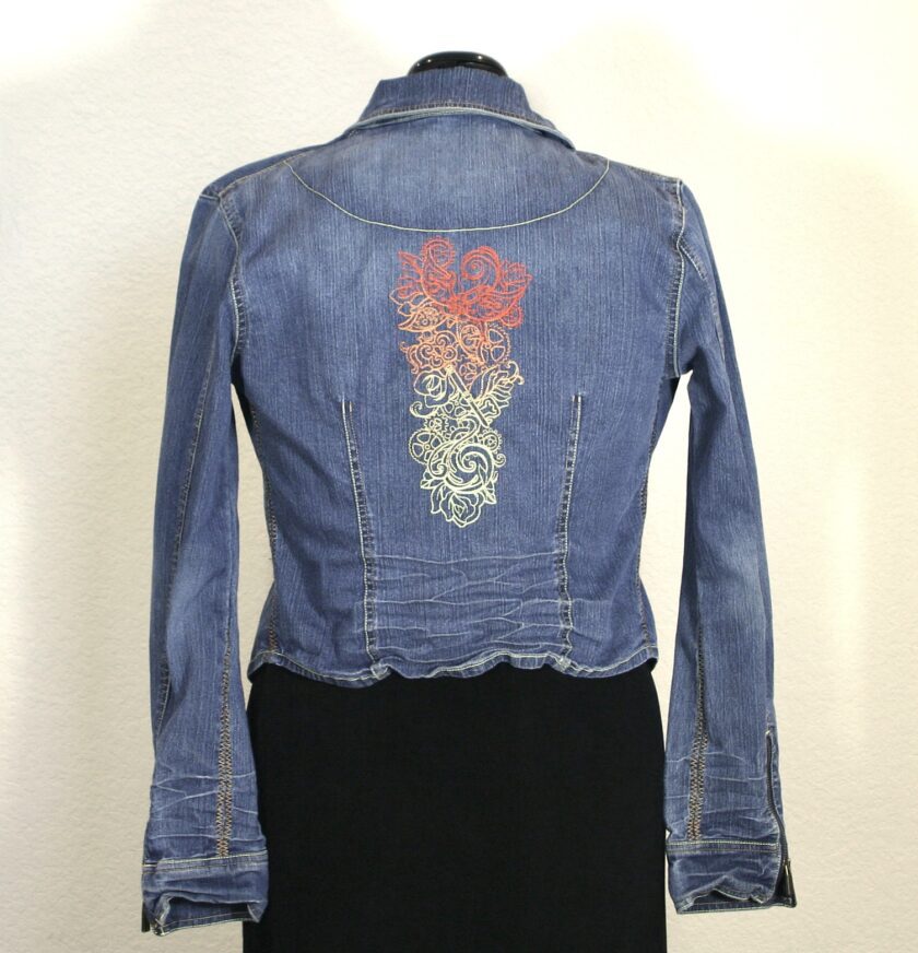 A denim jacket with an embroidered flower on it.