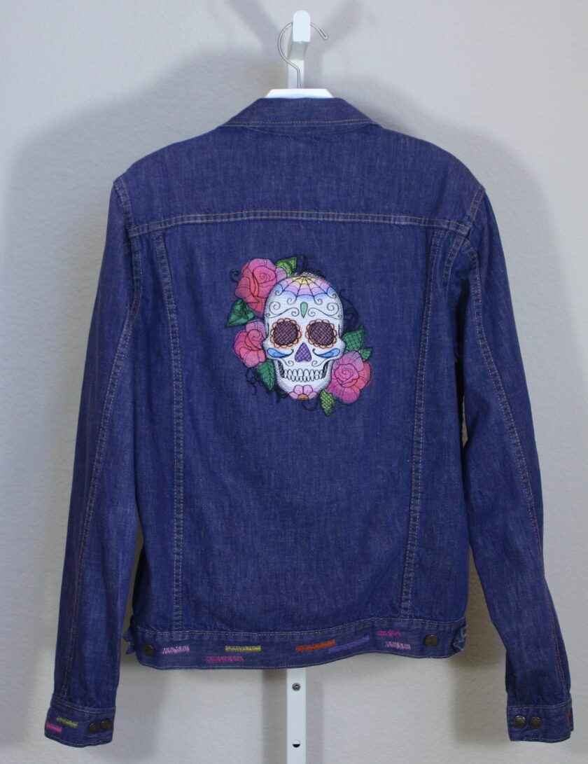 A denim jacket with a skull and roses embroidered on it.