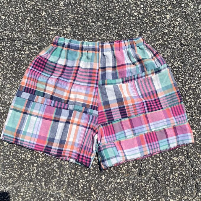A pair of colorful plaid shorts laying on the ground.