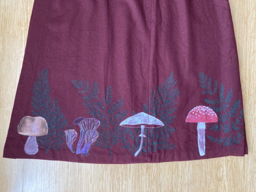 A burgundy skirt with mushrooms and ferns on it.