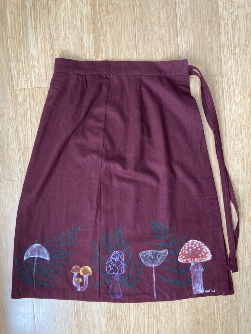 A maroon skirt with mushrooms and ferns on it.