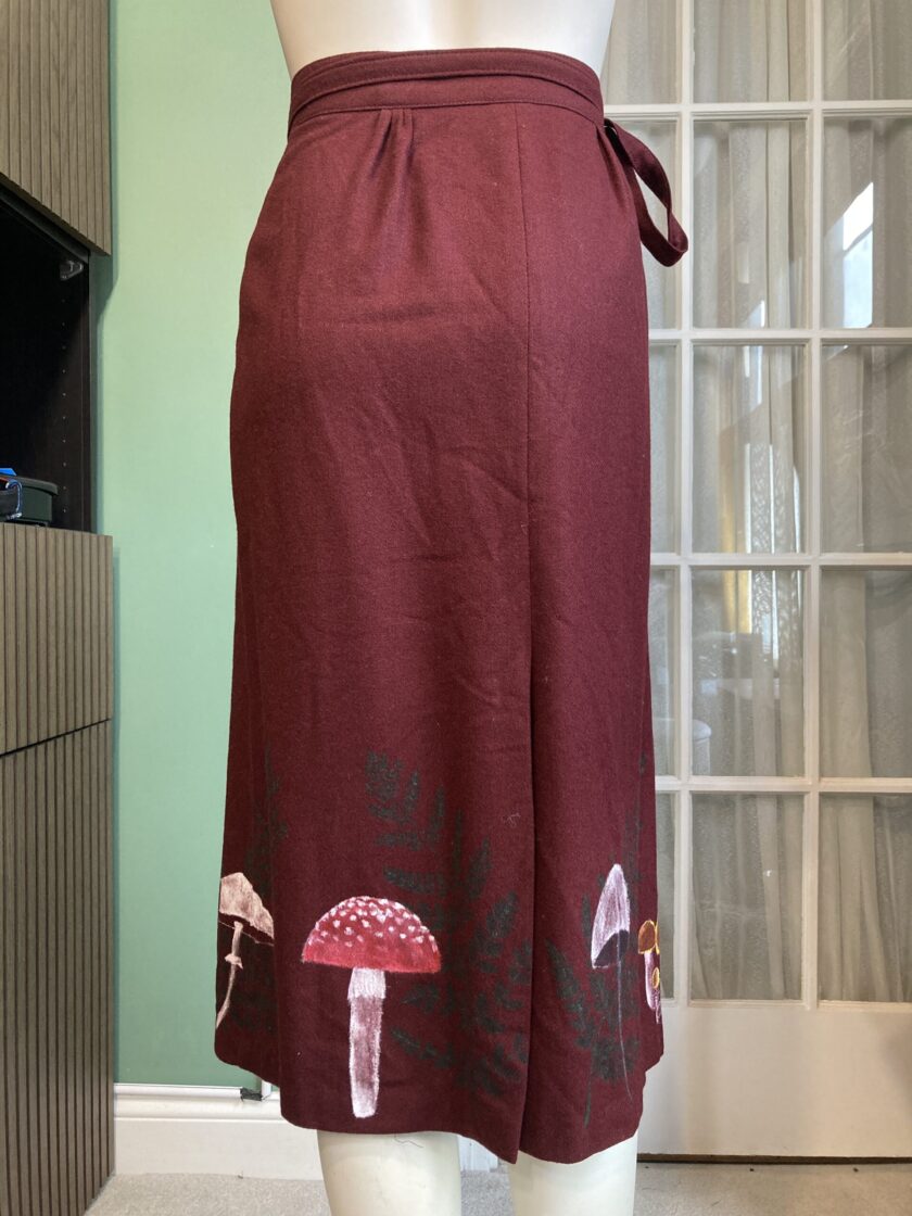 A mannequin wearing a burgundy skirt with mushrooms on it.