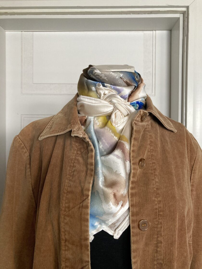 A mannequin wearing a tan jacket and scarf.