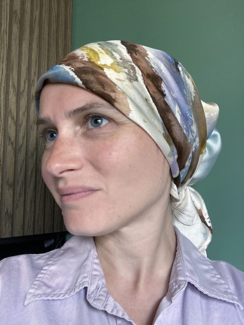 A woman wearing a hand-painted head scarf.