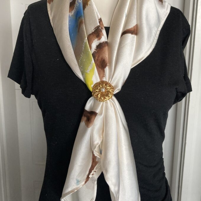 A white silk scarf with a gold buckle.