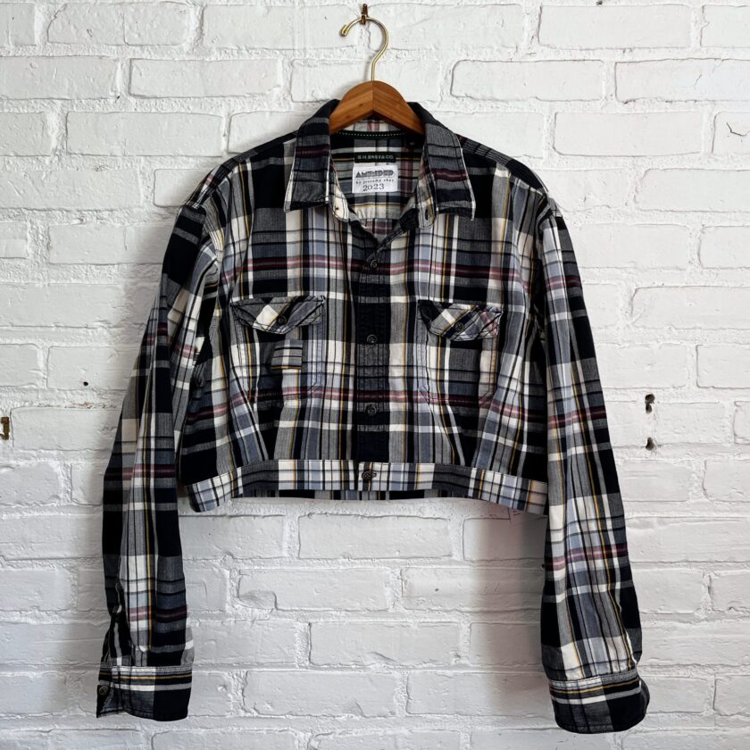 A navy and white plaid jacket hanging on a brick wall.
