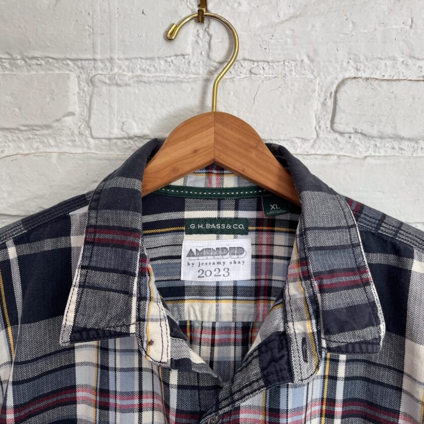A plaid shirt hanging on a white brick wall.