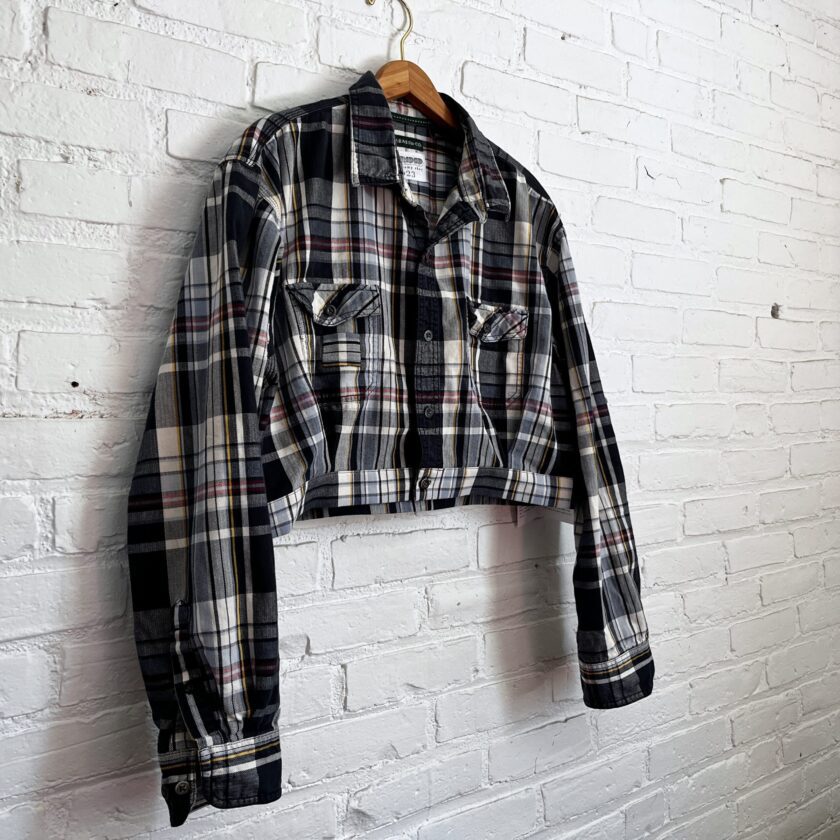 A black and white plaid shirt hanging on a brick wall.