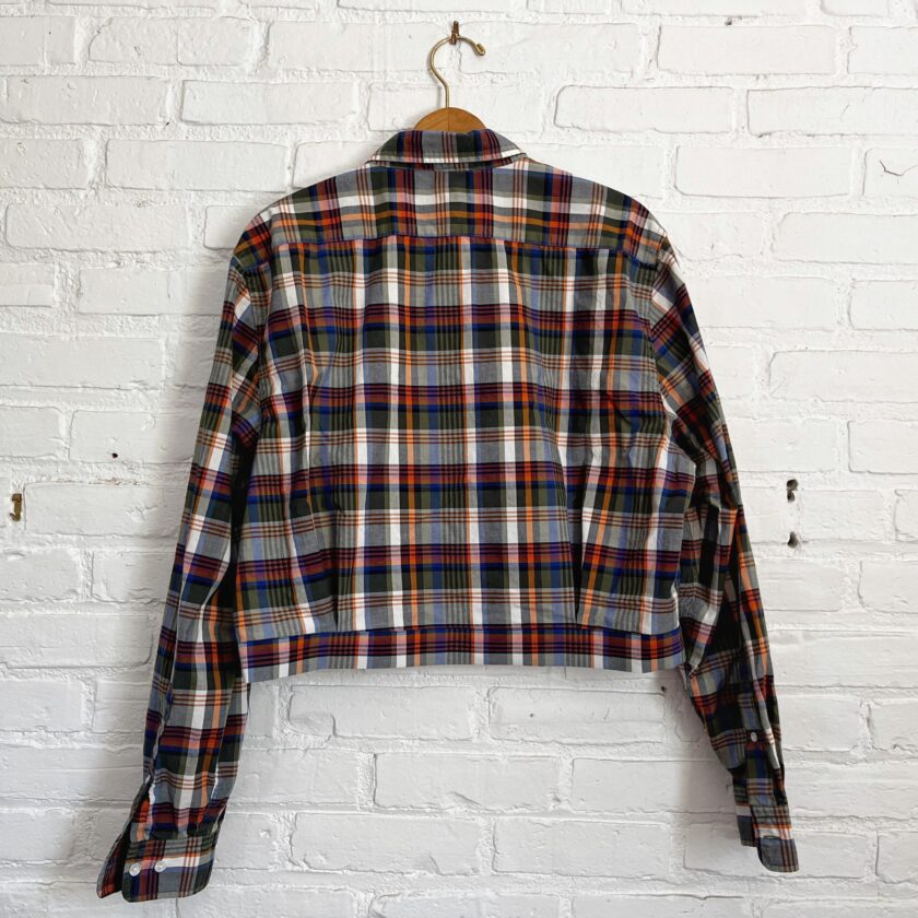 A plaid shirt hanging on a brick wall.