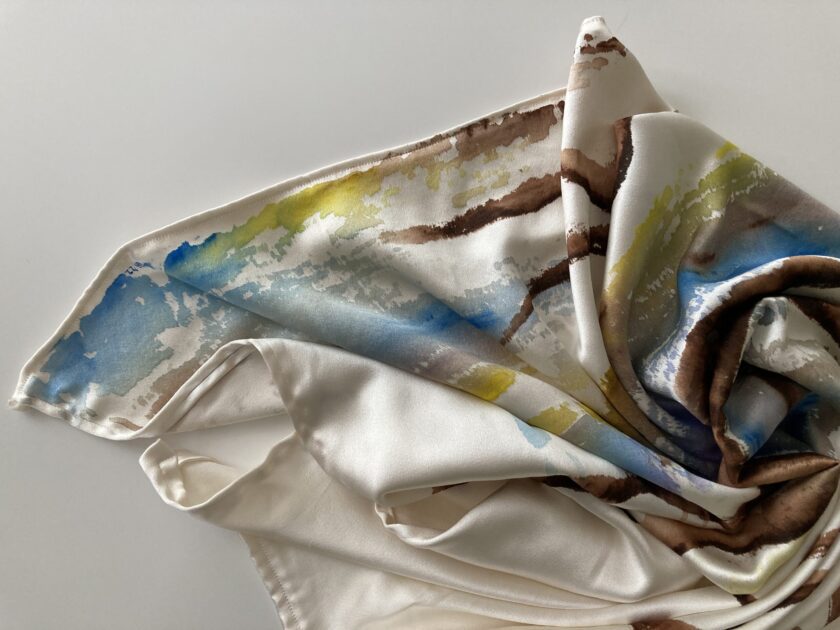 A white, blue, and yellow silk scarf on a white surface.