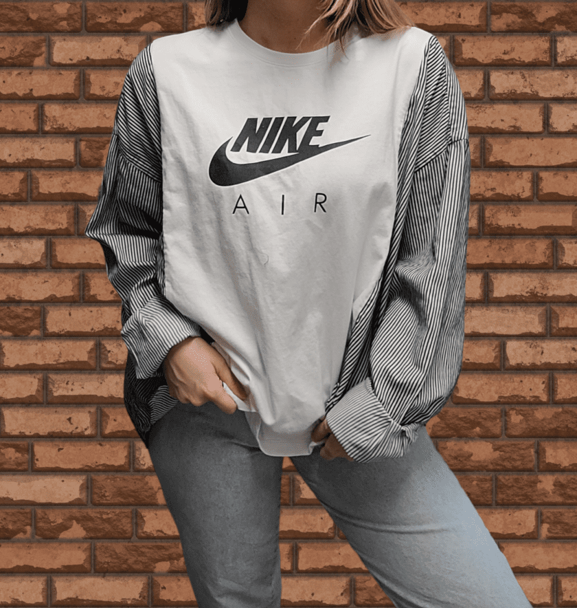 A woman wearing a nike air t - shirt in front of a brick wall.