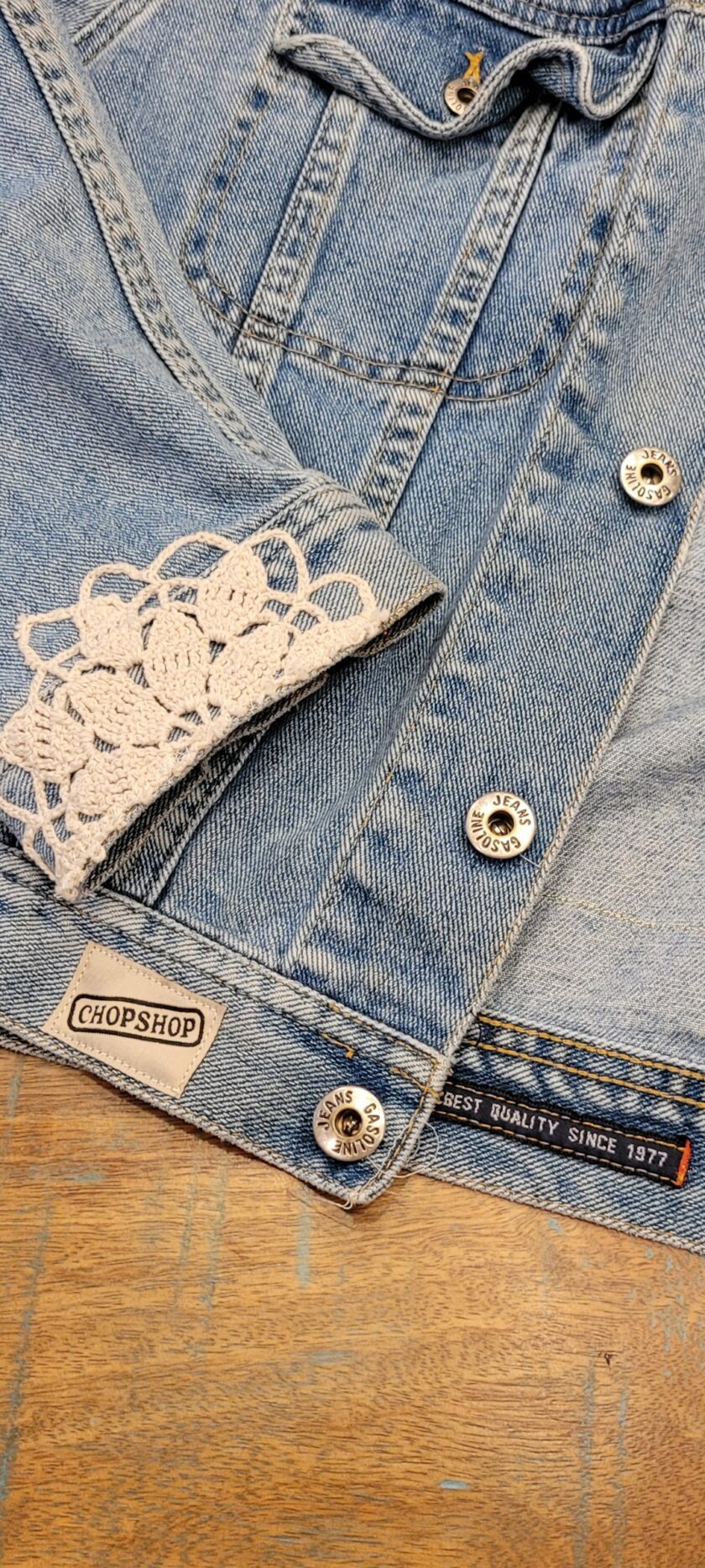 A close up of a denim jacket with lace on it.