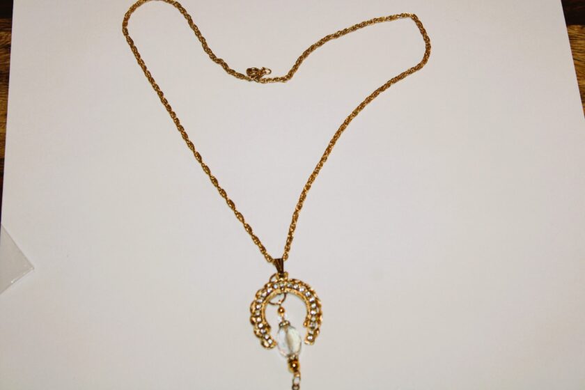 A gold necklace with a horseshoe on it.