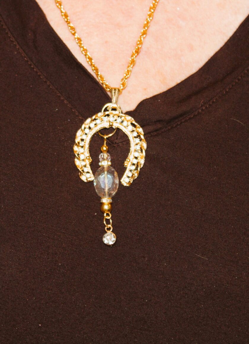 A woman is wearing a necklace with a horse on it.