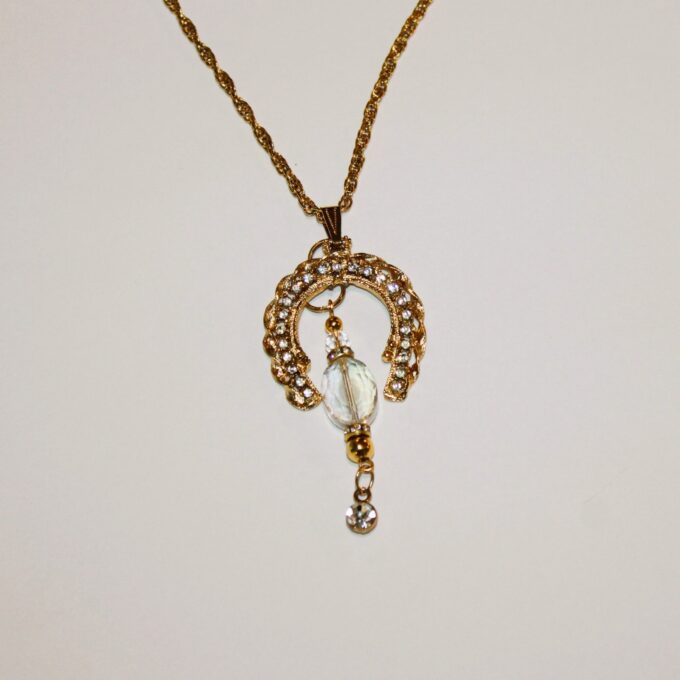 A gold necklace with a crystal pendant on it.