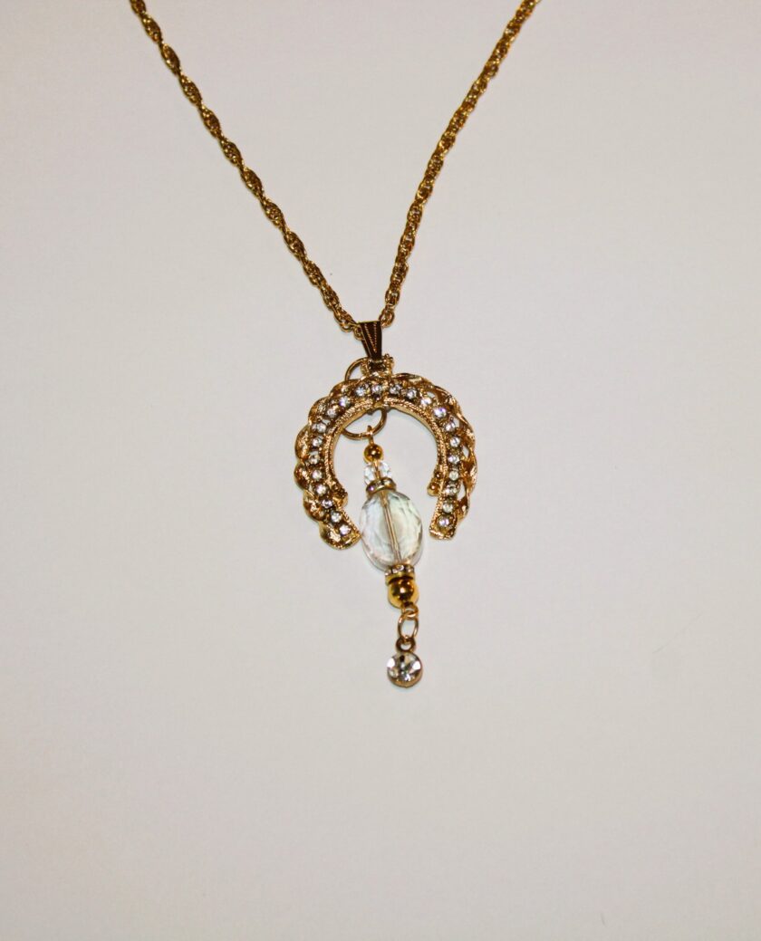 A gold necklace with a crystal pendant on it.