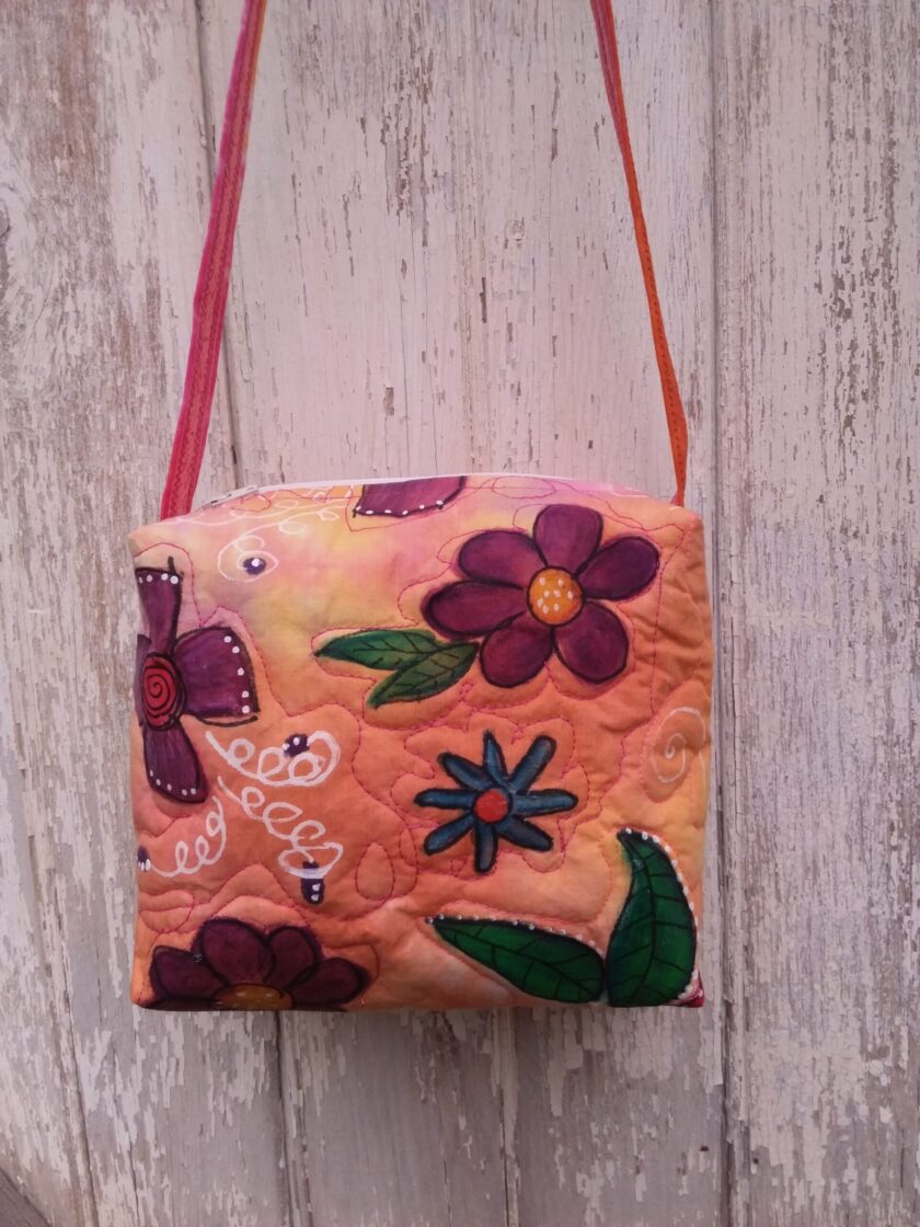 A unique upcycled bag with bold red, purple and blue flowers on an orange and pink fabric