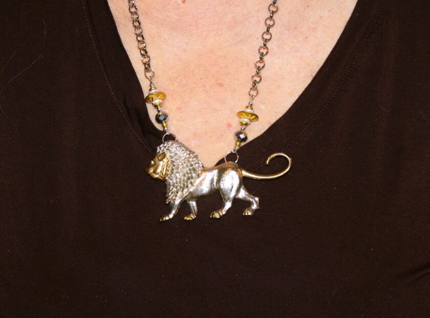 A woman wearing a necklace with a lion on it.