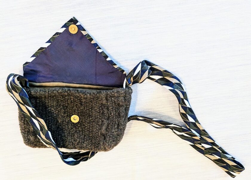 A small purse with a blue and black ribbon on it.